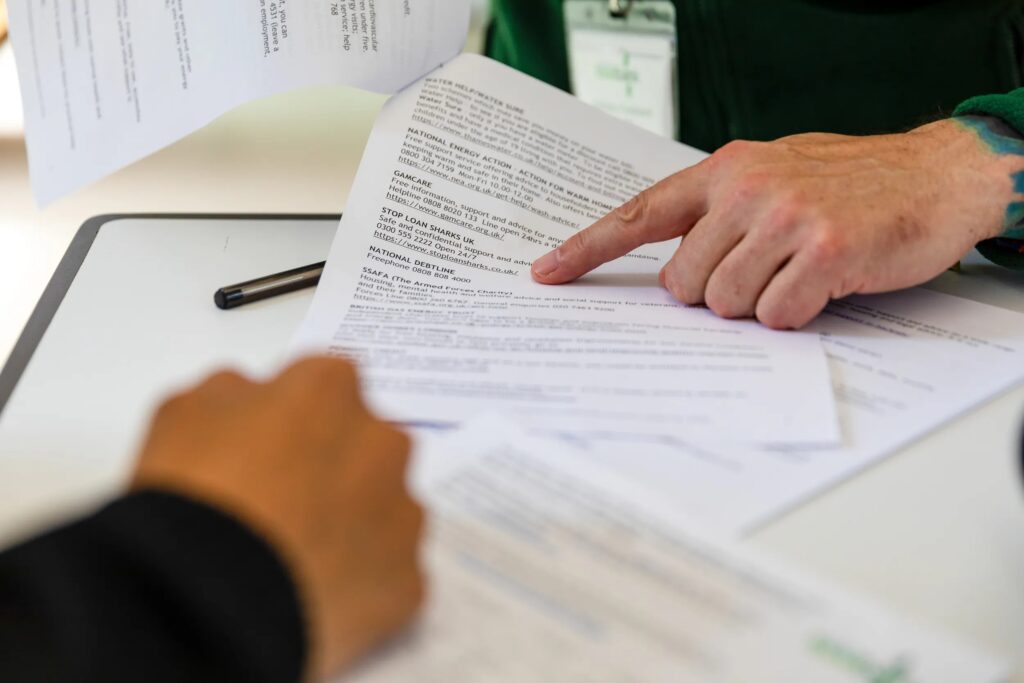 A leaflet on a desk with someone pointing at it