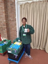 Volunteer poses with mug of tea beside crates